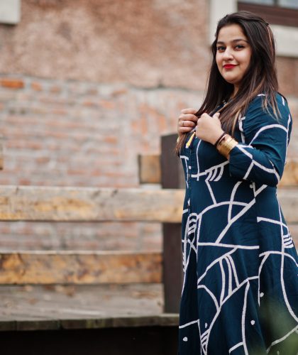 Brunette indian woman in long fashionable dress posed outdoor.